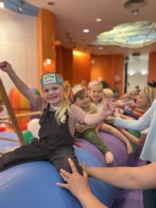Staff And Children Playing With A Parachute With Balloons On It